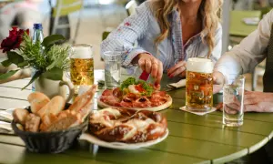 Un tavolo al birrificio Forst Lagundo con birra, salumi, pane e un pretzel.