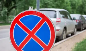 Znak b36 zakazu zatrzymywania się. Samochody stojące w rzędzie na poboczu drogi.