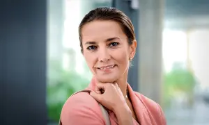 Uśmiechnięta Kamilla Baar, znana z filmów, seriali i programów, w różowej marynarce.