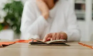 Osoba przegląda pieniądze, zastanawiając się nad wpływem stóp procentowych a inflacji na domowy budżet.