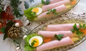 Szynka w galarecie z jajkiem i marchewką, ozdobiona natką pietruszki.