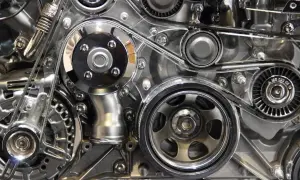 Détail d'un moteur chromé, avec la courroie de distribution tendue entre plusieurs poulies.