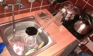 W kuchni, w zlewie prowizoryczny aparat do destylacji, w tle czajnik i garnki. Nastaw na bimber gotowy.