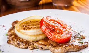 Karkówka pieczona w plastrach z cebulą i pomidorem. Aromatyczne danie, które zachwyci każdego smakosza.