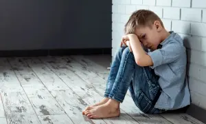 Smutny chłopiec siedzi skulony w kącie. Jeśli wiesz, gdzie zgłosić zaniedbanie dziecka przez matkę, nie wahaj się działać.