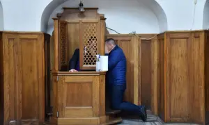 Mężczyzna klęczy przy konfesjonale, zasłaniając twarz. Czy w kościele anglikańskim jest spowiedź?