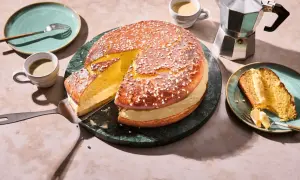Eine köstliche Tarte Tropezienne, aufgeschnitten und mit einer Kaffeetasse und einem Moka-Topf serviert.