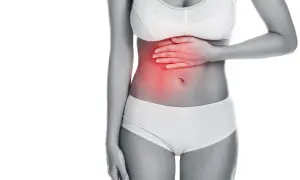Donna con mano sullo stomaco, evidenziato in rosso. Potrebbe cercare rimedi per il mal di stomaco.