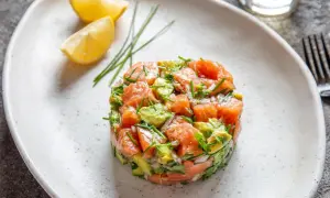 Un délicieux tartare de saumon frais, mélangé à de l'avocat et des herbes, servi avec des quartiers de citron.
