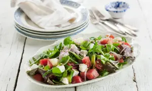 En fräsch sallad med vattenmelon, fetaost, tomater och gröna blad. Perfekt för en varm sommardag, den godaste melonsalladen!