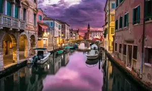 Un canal vénitien au crépuscule, avec des bateaux et des bâtiments colorés. Le ciel violet et rose, reflet de l'eau, illustre parfaitement ce qu'est le HDR.