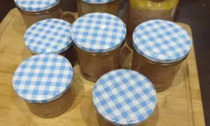 Mehrere Gläser mit selbstgemachter Leberwurst, verschlossen mit blau-weißen Karodeckeln, stehen auf einem Holzbrett.