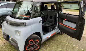 Citroën Ami, un quadriciclo elettrico compatto, con porte aperte e interni visibili. Il suo design unico e le dimensioni ridotte lo rendono perfetto per la città.