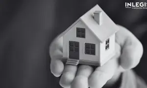 Miniatura domu na dłoni, symbolizująca ograniczone prawa rzeczowe i bezpieczeństwo posiadania.
