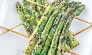 Grillspieße mit Spargel, Sesam und Kräutern auf einem weißen Teller. Perfekt zum Spargel grillen!