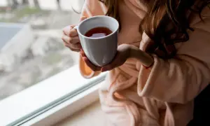 Kobieta w szlafroku trzyma kubek z herbatą. Zastanawiasz się, ile kofeiny ma herbata Earl Grey?