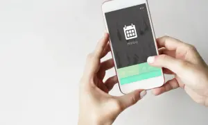 Dłonie trzymają telefon, na ekranie którego widnieje ikona kalendarza i napis "History". Chcesz usunąć historię przeglądania w telefonie?