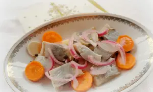 En vacker skål med sill till jul, dekorerad med morötter, lök och pepparkorn.