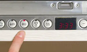 Palec wskazujący na panelu zmywarki Whirlpool, przycisk "eco" podświetlony na czerwono, cyfrowy wyświetlacz.