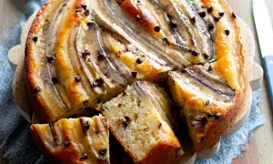 Delizioso dolce con banane mature e gocce di cioccolato, una fetta mostra la morbidezza dell'impasto.