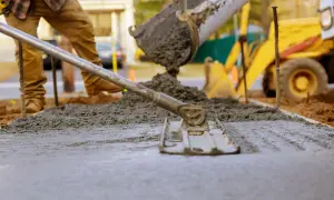Wylewanie i wyrównywanie świeżego betonu na budowie.