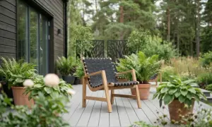En modern fåtölj med trästomme och flätad sits i plast står på en altan omgiven av grönska.