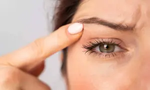 Gros plan sur un œil, une main touche la paupière supérieure.