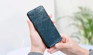 Dwie dłonie trzymają pęknięty telefon, czekając na wymianę dotyku.