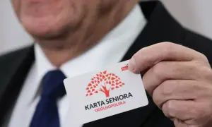 Mężczyzna prezentuje kartę seniora z czerwonym drzewem. To ogólnopolska karta uprawniająca do zniżek.