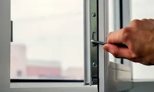 Dłoń używa klucza do regulacji okna, aby dopasować docisk skrzydła.
