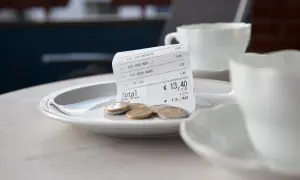 Rechnung mit Münzen auf einem Teller, bereit für das Trinkgeld nach dem Essen auf Sardinien.