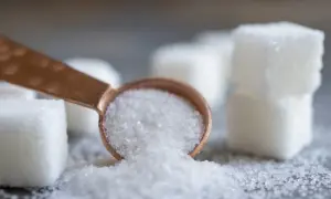 Łyżeczka z kryształkami, obok kostki cukru. Czy to sorbitol? Ten słodzik jest często używany jako zamiennik cukru.
