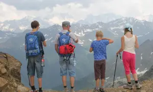 Familie genießt die Aussicht bei einer Bergtour mit Kindern. Die beeindruckende Berglandschaft erstreckt sich bis zum Horizont.
