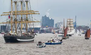 Große Segelschiffe und Dampfer nehmen an der einlaufparade hafengeburtstag teil, mit der Elbphilharmonie im Hintergrund.