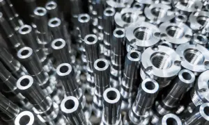 Metalowe elementy, precyzyjnie wykonane przez toczenie CNC, tworzą gęsty wzór. Widać gwintowane części i cylindryczne detale.