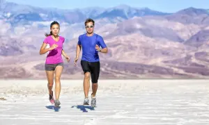 Coppia corre nel deserto, un allenamento intenso per come migliorare la resistenza. Montagne sullo sfondo.