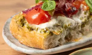Bruschetta au pesto, tomates fraîches, mozzarella fondante et oignons rouges sur une tranche de pain grillé. Un délice !