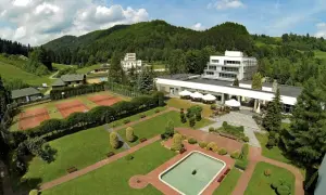Widok z lotu ptaka na hotel i korty tenisowe w otoczeniu zielonych wzgórz. To Rytro, perła południa, z basenem i zadbanym ogrodem.