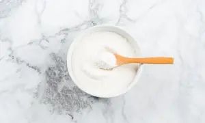 Weißes Pulver in einer Schüssel mit Holzlöffel, ideal um die Kollagenproduktion anzuregen.
