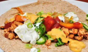 Tortilla garnie de poulet, poivrons, oignons, jalapeños, sauce au fromage et crème aigre. Une délicieuse recette tortilla à déguster !