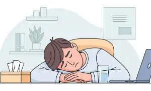 Ein Mann schläft erschöpft auf seinem Schreibtisch ein, ein Glas Wasser und Taschentücher daneben. Ein Bild für stillen Burnout.