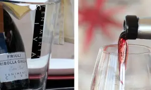 Un bicchiere si riempie di vino rosso, mostrando come si versa il vino. A sinistra, una bottiglia di Ribolla Gialla è in un secchiello.