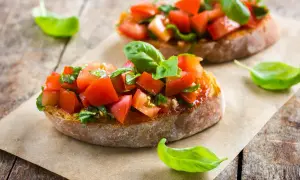 Frische Bruschetta-Rezepte: geröstetes Brot mit Tomaten, Knoblauch und Basilikum, garniert mit Basilikumblättern.