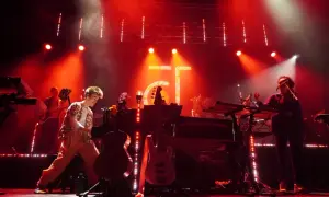 Jacob Collier and his band perform on a stage bathed in red light, with instruments and a large "GT" logo visible.