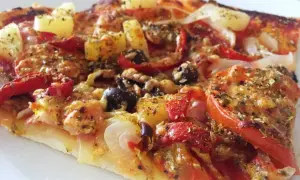 En bit pizza med ananas, oliver och paprika. Ett perfekt glutenfri pizzadeg recept för en god middag.