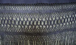 Detalle de cómo hacer flecos para mantones, con un intrincado tejido de macramé y borlas.