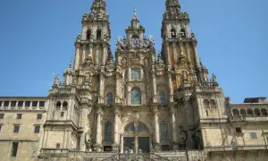 Majestatyczna katedra w Santiago de Compostela z trzema wieżami i schodami, po których wchodzą pielgrzymi.