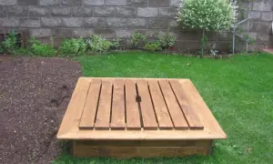 Nybyggd sandlåda i trä, redo för lek. Perfekt för att bygga sandslott i trädgården.