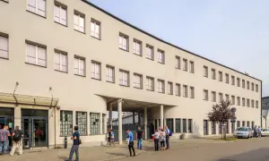 Dawna fabryka Oskara Schindlera w Krakowie, dziś muzeum. Na fasadzie widoczne okna i wejście, przed którym stoją ludzie.