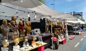 Bancarelle colorate alla fiera di Fano, con manichini dorati che indossano sciarpe e foulard.